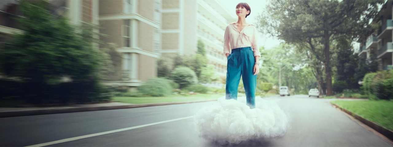Mujer sobre una nube en una carretera. Banner de servicios de movilidad Kinto