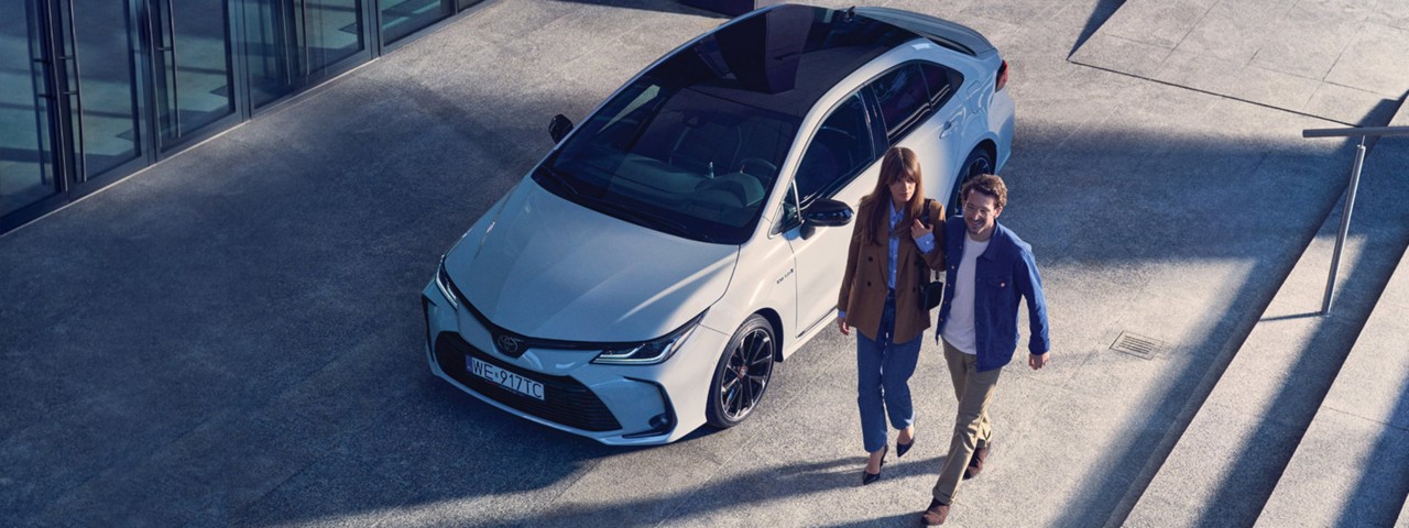 Kobieta i mężczyzna na drodze obok Toyoty Corolla