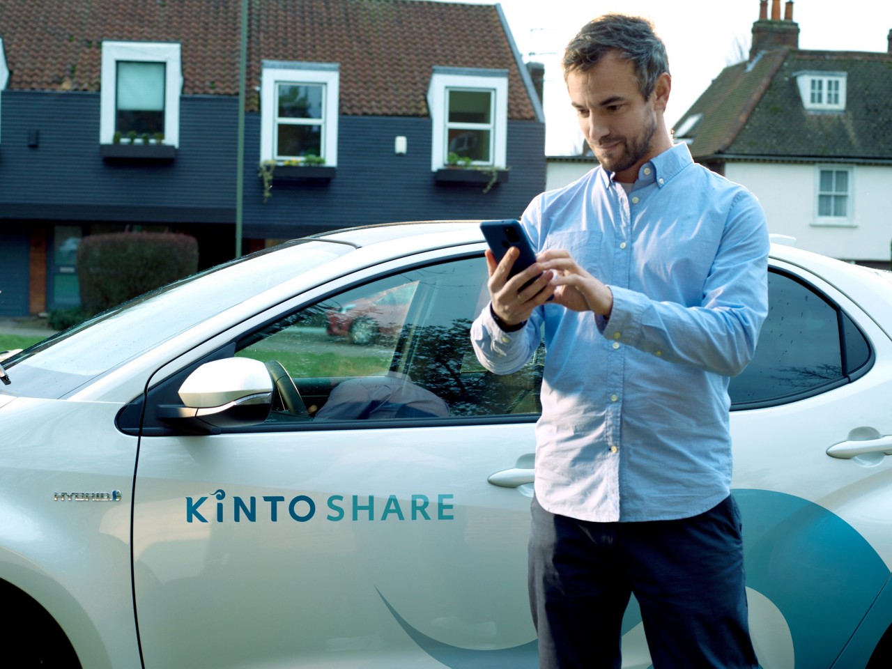 Hombre frente a un coche consultando Kinto Share